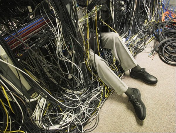 Photograph of hosting technician trying to fix messy data center.